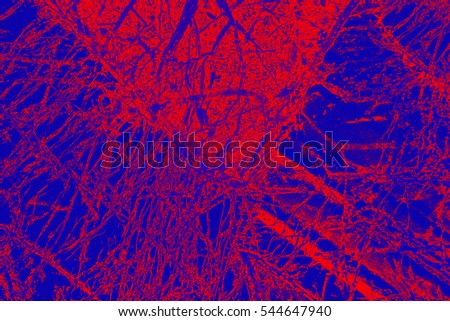 Dramatic red wedge with "hairs" trailing from its edges slices into blue background in abstract micrograph of peridotite rock, at 40x with polarization.