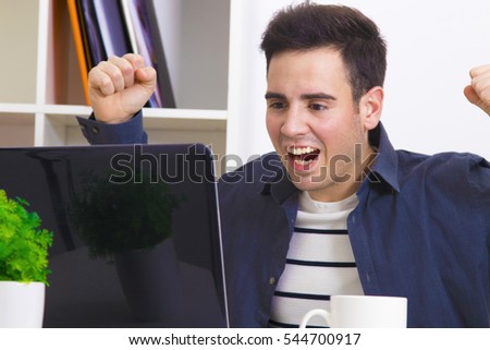 male young celebrating with enthusiasm ahead of the computer laptop
