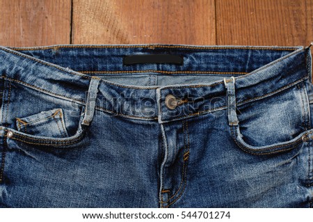 Details from blue jeans-wooden background