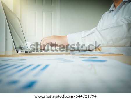 Business man working at office with laptop and documents on his desk, Financial graph data.