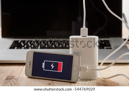 A smartphone with the power bank in the foreground of the camera. Nescessity to take a charger with the phone with a weak battery.