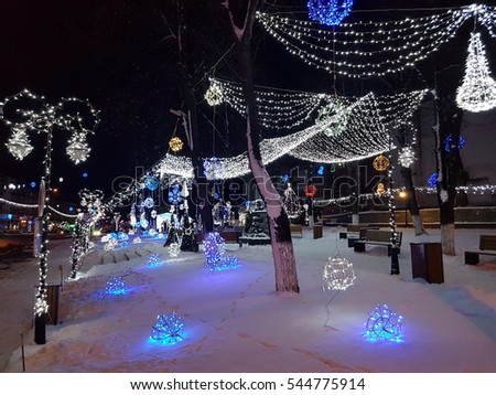 Traditional decorative Christmas lights in the city. Multiple decoration made from lights, white, blue, in the night. Europe city landscape