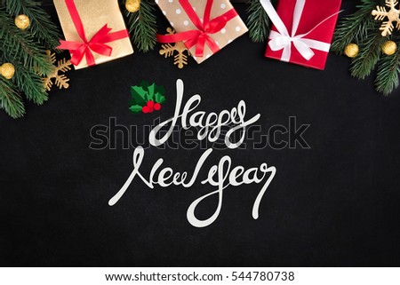 Happy New Year text on blackboard background with gift boxes and decorating items