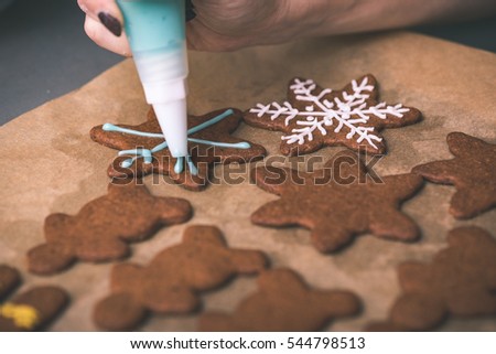 Womans hand decorating cookies with sugar. Making Gingerbread Cookies Series. - vintage effect