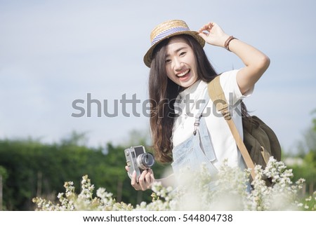 Asian hipster cute teen girl with camera in white flower garden,  vintage tone travel and relax with nature concept. 