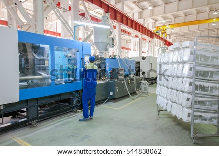 Industrial injection molding press machine for the manufacture of conditioner parts using polymers in the management of worker Royalty-Free Stock Photo #544838062