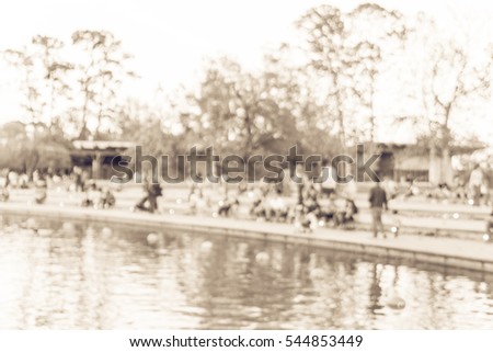 Blurred image people sitting and enjoying fresh air on stairs toward the lake at Houston, Texas, US. Defocused background outdoor activities of crowd people near the lake in city park at sunset.