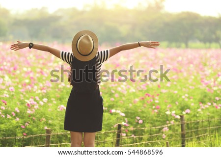 Beauty Girl Outdoors enjoying nature. Beautiful Teenage Model girl in black dress standing  on the Spring Field, Sun Light. freedom concept Royalty-Free Stock Photo #544868596