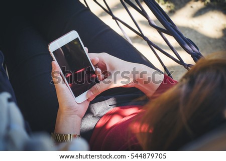 A  bright day of a young woman holding and using  smartphone