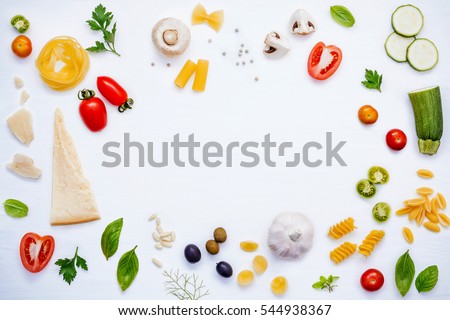 Italian food concept .Various kind of pasta with ingredients sweet basil ,tomato ,garlic ,parsley ,bay leaves ,pepper ,champignon,zucchini and parmesan cheese on white wooden background flat lay. Royalty-Free Stock Photo #544938367