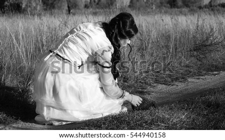 The girl touches a live hedgehog on the country road. Girl and hedgehog.