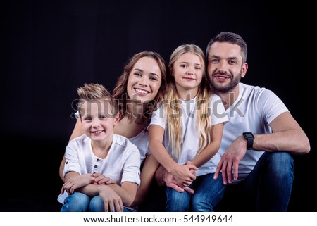 Happy family sitting together and smiling at camera isolated on black