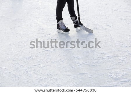Outdoor Ice skating. Hockey player's legs and skates on ice rink.