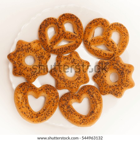 Curly Biscuits with poppy seeds on a white plate on a white background
