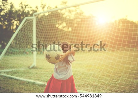 Close up picture of an old ball and foot of a girl who is playing football in the sunshine day.