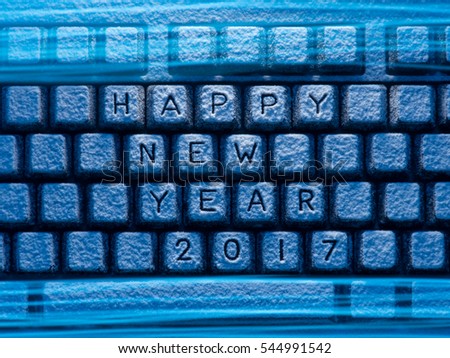 keyboard covered with snow with words Happy New Year and 2017 illuminated with blue light