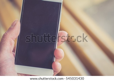 Man holding cell phone. Cell phone in hand. Outdoor. Blurred background.