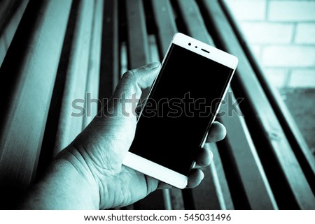 Man holding cell phone. Cell phone in hand. Outdoor. Blurred background.