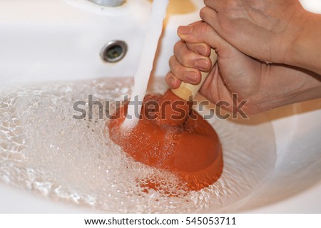 Woman with  plunger trying to remove clogged sinks. Abstract photo. Royalty-Free Stock Photo #545053711