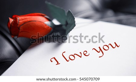 red rose lying next to a piece of paper and the words I love you written on it