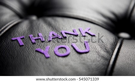 the word Thank You in purple on black leather