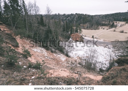 frozen river in winter with sandstone cliffs and ice blocks. Gauja National Park. Latvia. - vintage film effect