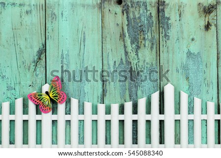 White picket fence with colorful butterfly by antique rustic mint green wood background; colorful springtime sign with wooden painted copy space