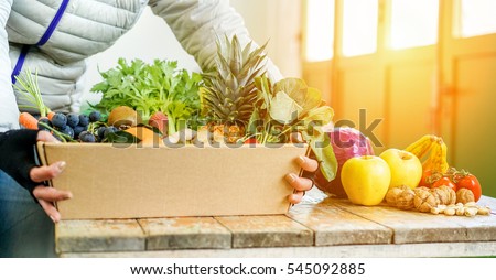 Fruit seller woman with different fruits and vegetables in shop  - Worker preparing fruit ecological paper basket - Vegetarian and vegan concept - Focus on pineapple kiwi grapefruit - Warm filter