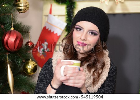 Beautiful girl drinking tea next to Christmas tree