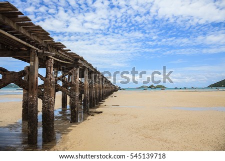 Wooden jetty bridge on low tide with blue sky background