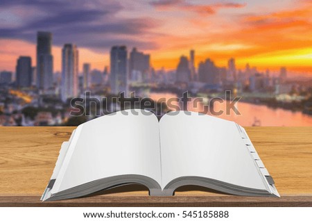 Open book on wooden table with blurred cityscape background.