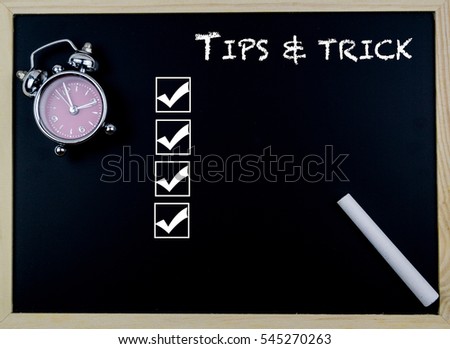 Tips and Trick word with clock on table in front of chalkboard