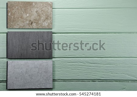 3 pieces of stone texture sample laminate on green color pastel color wooden background.Samples of laminate, stone , click lock laminate texture floor tile on green color wood paint Background.