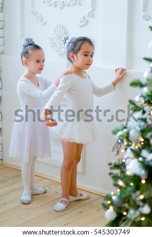 Two young ballet dancers learning the lesson near Christmas tree. Try some new pose