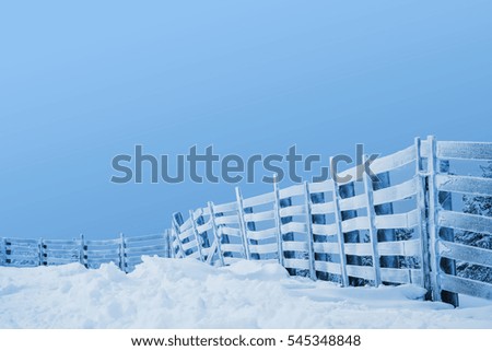 snowy wooden fence on a cloudy day