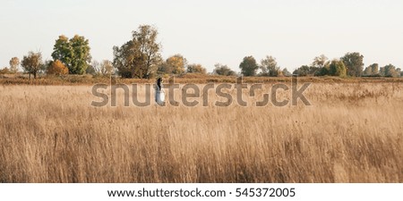 The girl with long black hair walks across the field in the autumn