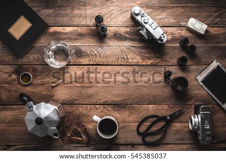 Camera, roll of films, notebook, coffee cup, coffee maker on wooden table. Artist, photographer workspace.