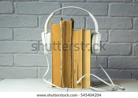 old dilapidated book with large white headphones / audio-book with white headphones 
