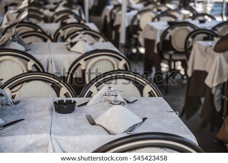 Table and chairs in empty beach restaurant during sunset.  fork on the table wedding dinner.  Served table in restaurant, closeup. cafe background