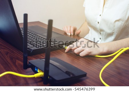 woman working in the office trying to connect the Internet cable to the connector on the laptop for a good Internet connection. the concept of wired and wireless Royalty-Free Stock Photo #545476399