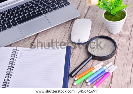 Laptop, notebook with magnifying glass on wooden table