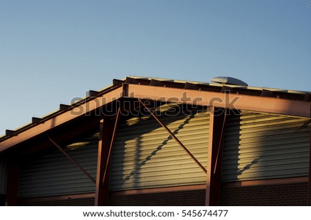 Frame bracing on warehouse roof and wall during sun set.