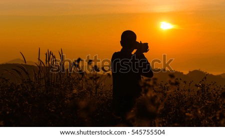 Silhouette of a young who like to travel and photographer, taking pictures of the beautiful moments during the sunset ,sunrise.