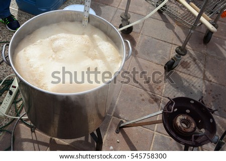 Beer brewing kettle on patio about to foam over with hot break