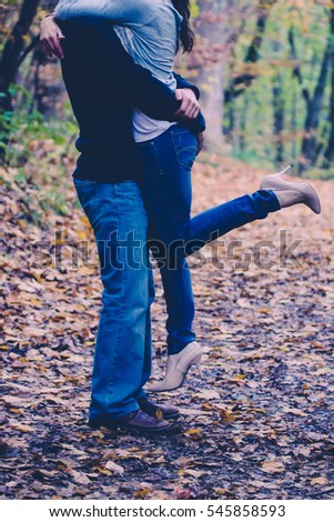 Man lifts up woman on romantic nature walk.