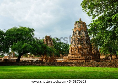 Pagodas are dominantly in historic centre of Ayutthaya, Thailand. Tree and grass are foreground, blue sky is background of picture. Fourth view.