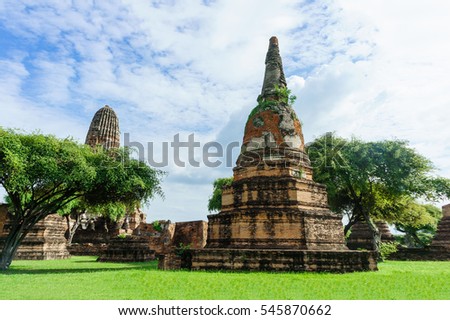 Pagoda are dominantly in historic centre of Ayutthaya, Thailand. Tree and grass are foreground, blue sky is background of picture.