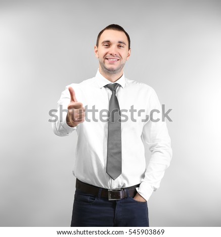Handsome man showing thumb up sign, on light background