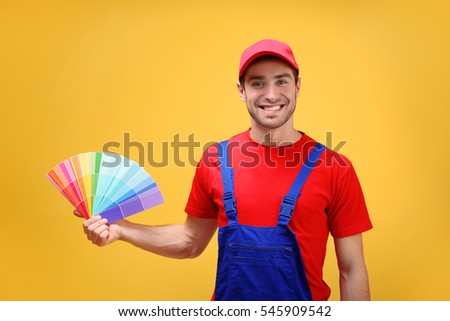Handsome young decorator with color samples on yellow background