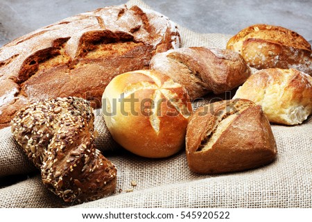 Different kinds of bread rolls on black board from above. Kitchen or bakery poster design. Royalty-Free Stock Photo #545920522